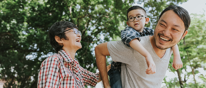 Asian Family Laughing with Kid on Dad's Back Outside