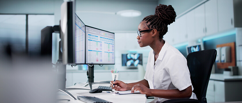 Woman with Pen Looking at Computer Spreadsheet on Screen